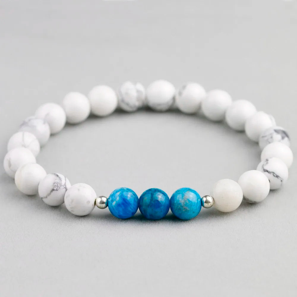 Armband aus Naturstein mit Apatit- und Howlite-Perlen auf grauem Hintergrund