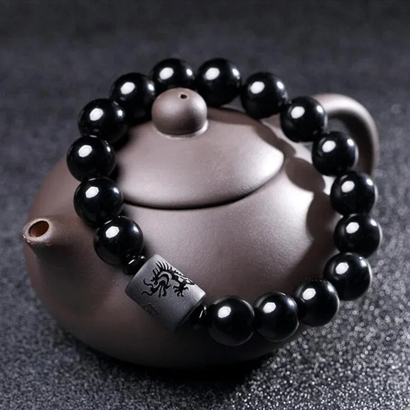 Armband mit Turmalinperlen im ethnischen Stil auf einer Teekanne auf grauem Hintergrund